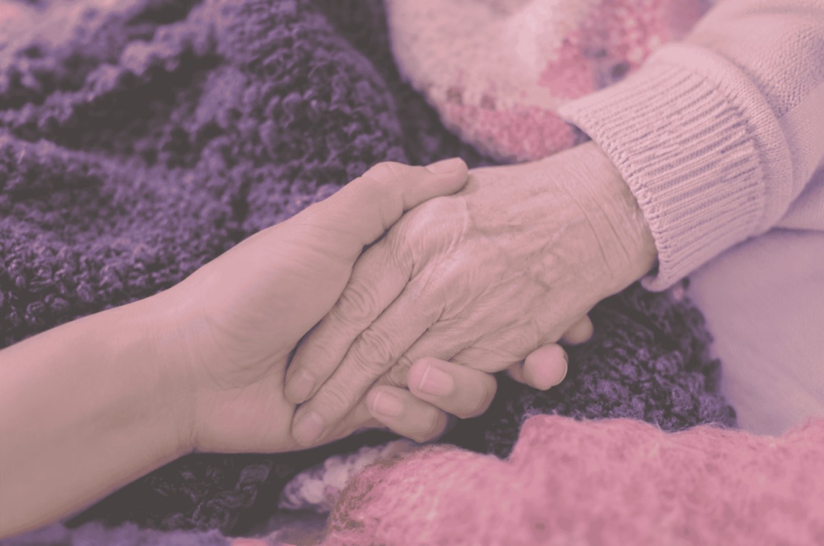 A younger hand gently holding an older person's hand